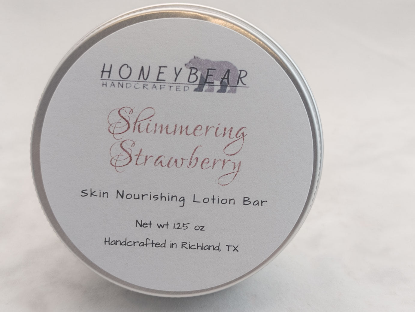 Shimmering Strawberry lotion bar in a silver tin on white background. Luxurious skin nourishing lotion bar. Romantic scent.